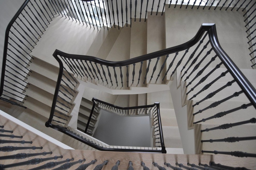 ボストンにあるラグジュアリーな巨大なトランジショナルスタイルのおしゃれな折り返し階段 (ライムストーンの蹴込み板、金属の手すり) の写真