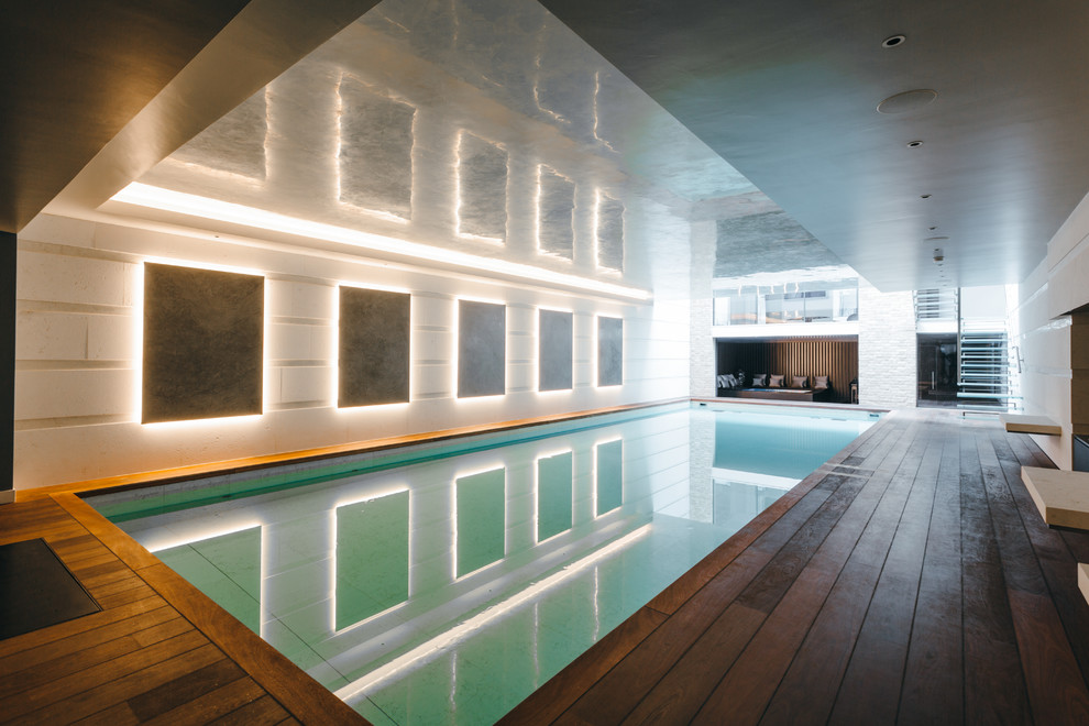 Large contemporary indoor rectangular pool in London with a pool house and decking.