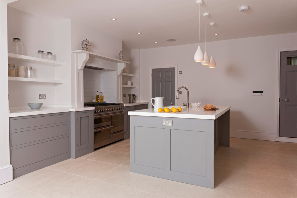 This is an example of a mid-sized transitional kitchen in London with grey cabinets, with island, an undermount sink, shaker cabinets, solid surface benchtops, white splashback, subway tile splashback, stainless steel appliances and porcelain floors.