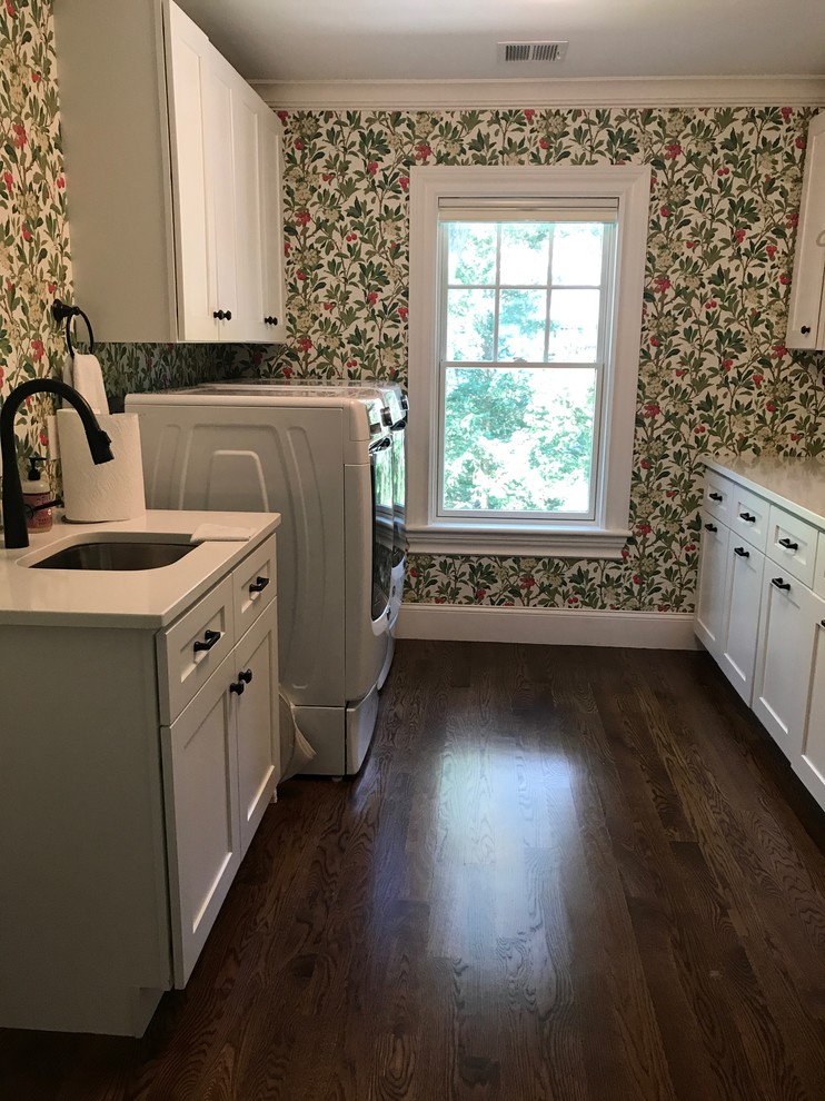 Mid-sized traditional galley dedicated laundry room in Boston with an undermount sink, shaker cabinets, white cabinets, quartz benchtops, medium hardwood floors, a side-by-side washer and dryer, brown floor and multi-coloured walls.
