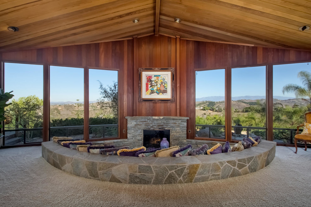 Inspiration for a midcentury open concept living room in San Diego with brown walls, carpet, a standard fireplace and a stone fireplace surround.