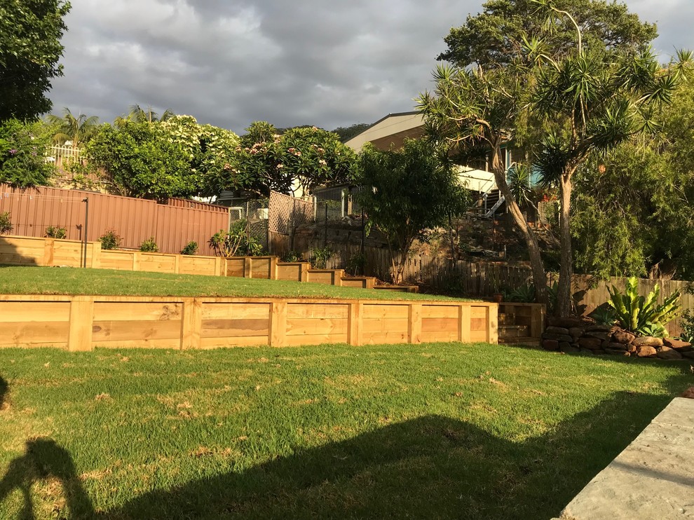 This is an example of a mid-sized contemporary backyard full sun xeriscape for summer in Wollongong with a retaining wall.