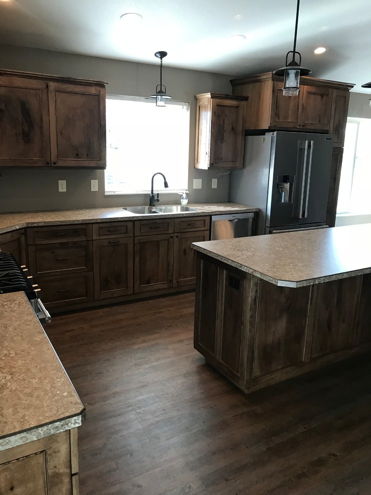 Large mountain style l-shaped medium tone wood floor and brown floor kitchen photo with an undermount sink, recessed-panel cabinets, medium tone wood cabinets, stainless steel appliances, an island and laminate countertops