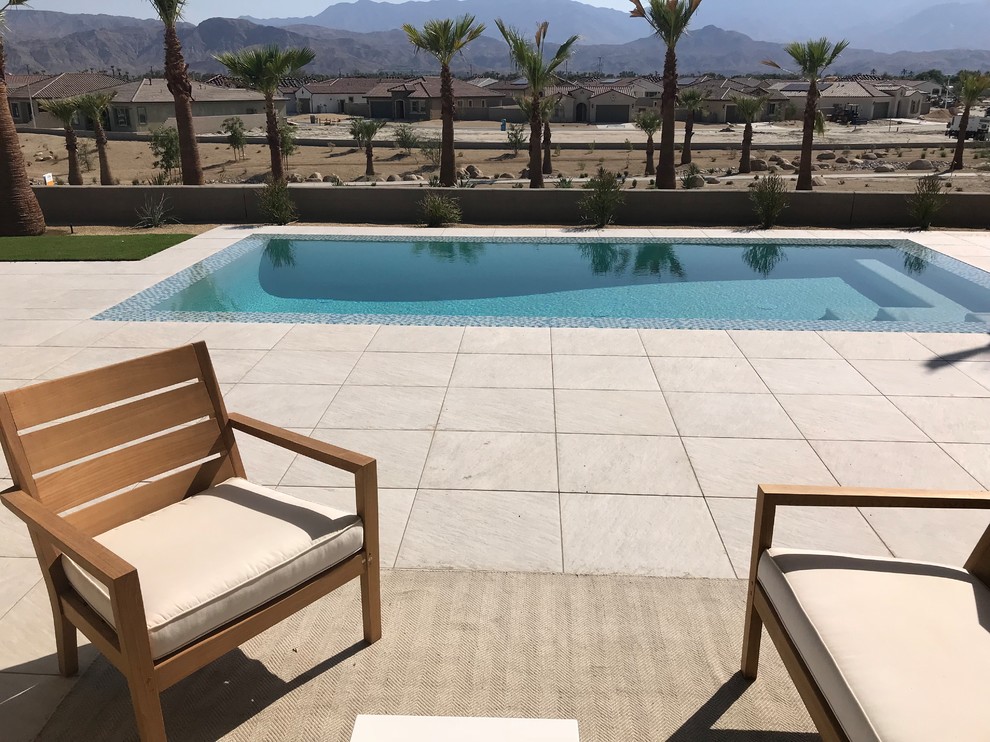 Foto de piscina infinita minimalista grande rectangular en patio trasero con suelo de baldosas