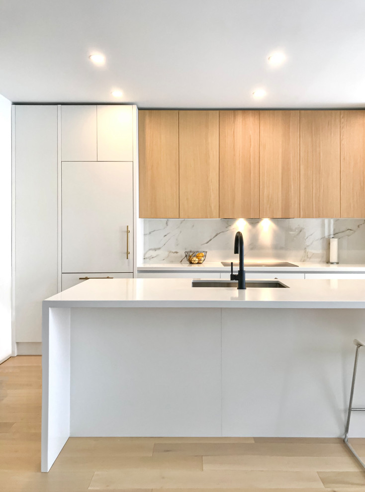 Einzeilige, Mittelgroße Moderne Wohnküche mit flächenbündigen Schrankfronten, weißen Schränken, Quarzwerkstein-Arbeitsplatte, Küchenrückwand in Weiß, Rückwand aus Quarzwerkstein, hellem Holzboden, Kücheninsel und weißer Arbeitsplatte in Toronto