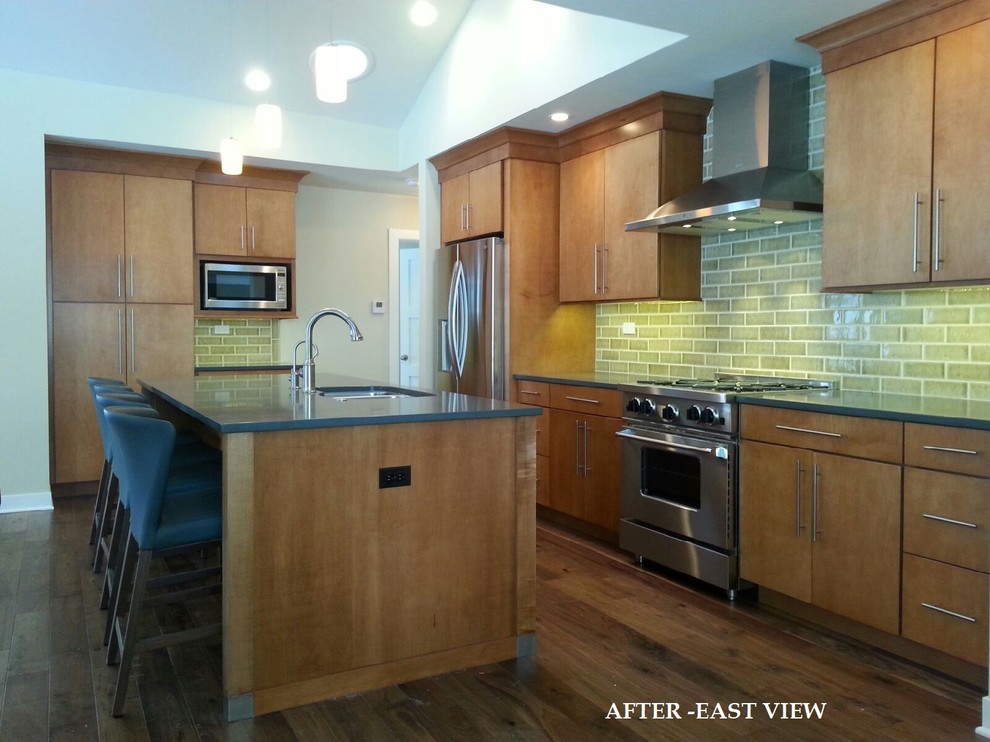 This is an example of a midcentury kitchen in Chicago with an undermount sink, medium wood cabinets, solid surface benchtops, green splashback, ceramic splashback, stainless steel appliances, medium hardwood floors and with island.