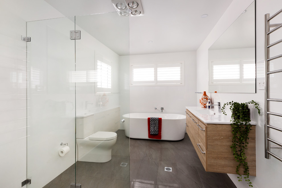 Photo of a mid-sized contemporary bathroom in Sydney with brown cabinets, a freestanding tub, white tile, white walls, an integrated sink, engineered quartz benchtops, white benchtops and flat-panel cabinets.