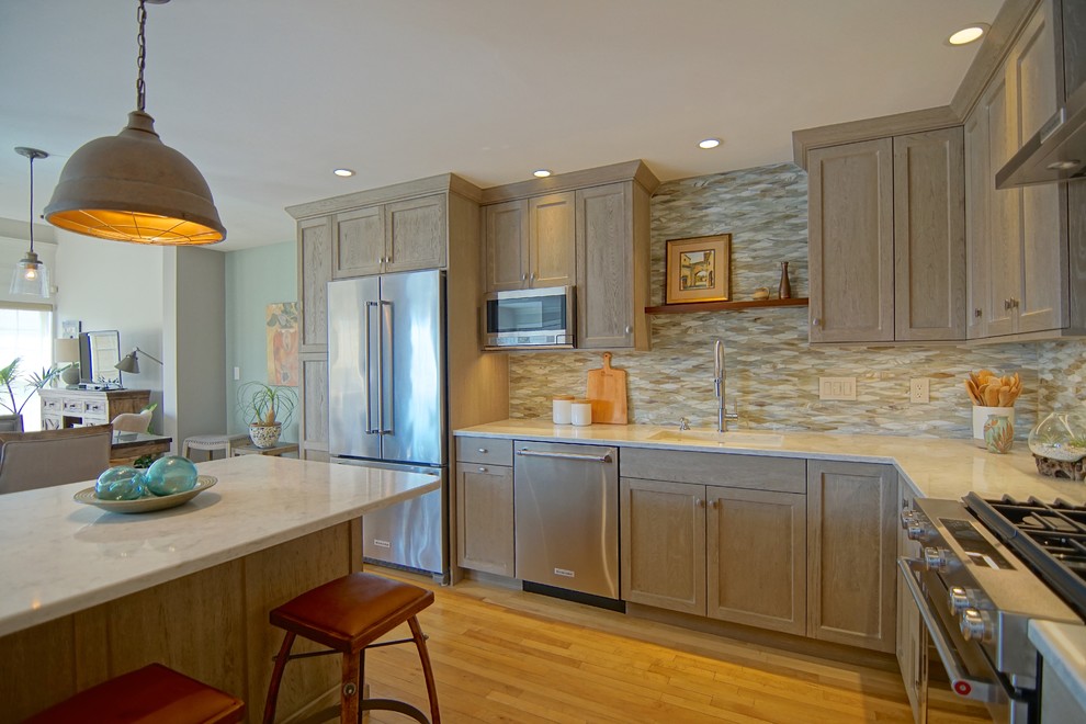 Example of a mid-sized transitional l-shaped medium tone wood floor and beige floor eat-in kitchen design with an undermount sink, beaded inset cabinets, distressed cabinets, marble countertops, gray backsplash, ceramic backsplash, stainless steel appliances, an island and white countertops