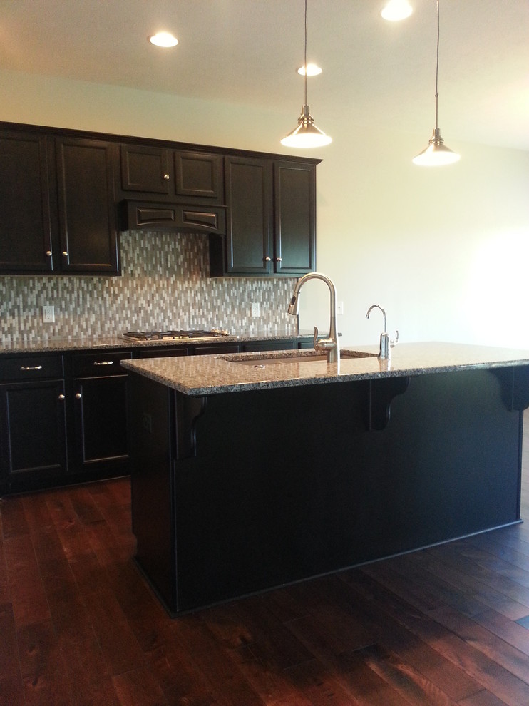 Eat-in kitchen - traditional l-shaped eat-in kitchen idea in Omaha with an undermount sink, recessed-panel cabinets, dark wood cabinets, granite countertops, gray backsplash, stone tile backsplash and stainless steel appliances