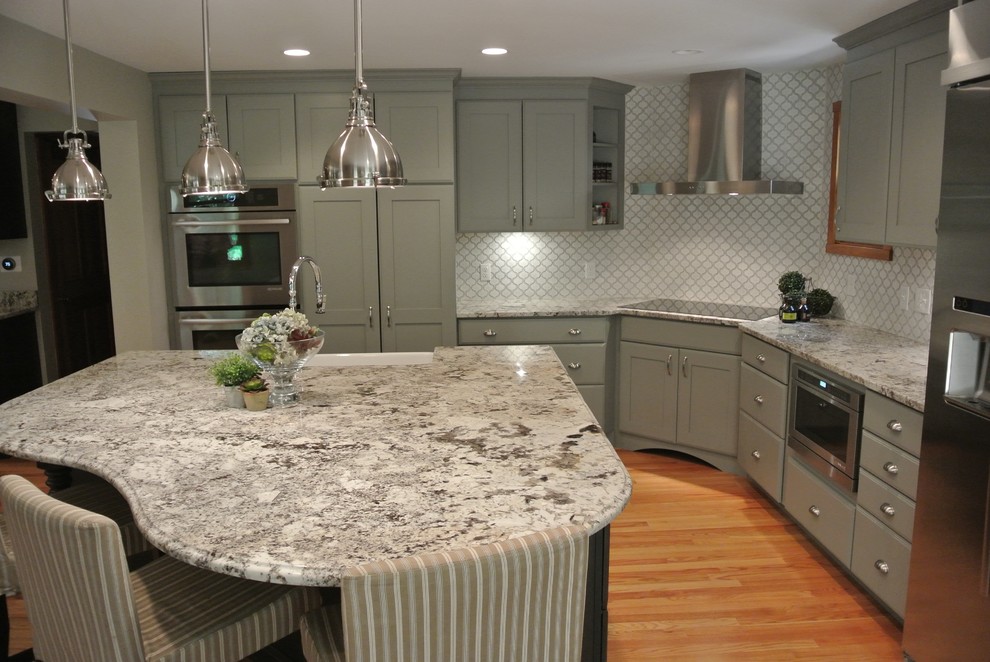 Inspiration for a large transitional l-shaped light wood floor eat-in kitchen remodel in Boston with a farmhouse sink, shaker cabinets, gray cabinets, granite countertops, white backsplash, ceramic backsplash, stainless steel appliances, an island and gray countertops