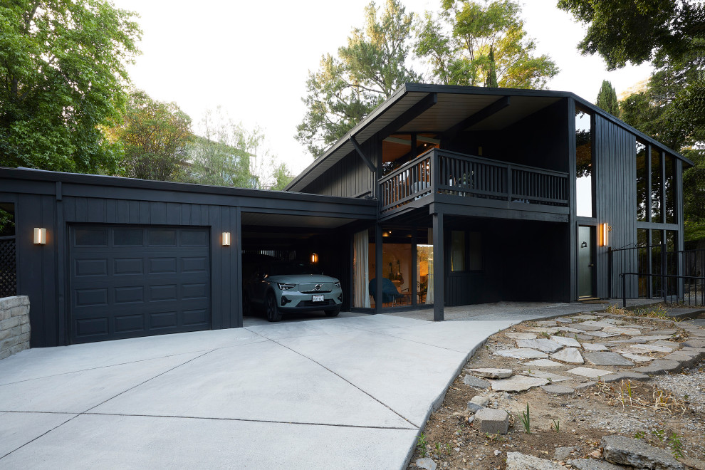 Inspiration pour une façade de maison noire vintage en bois de taille moyenne et à un étage avec un toit plat.