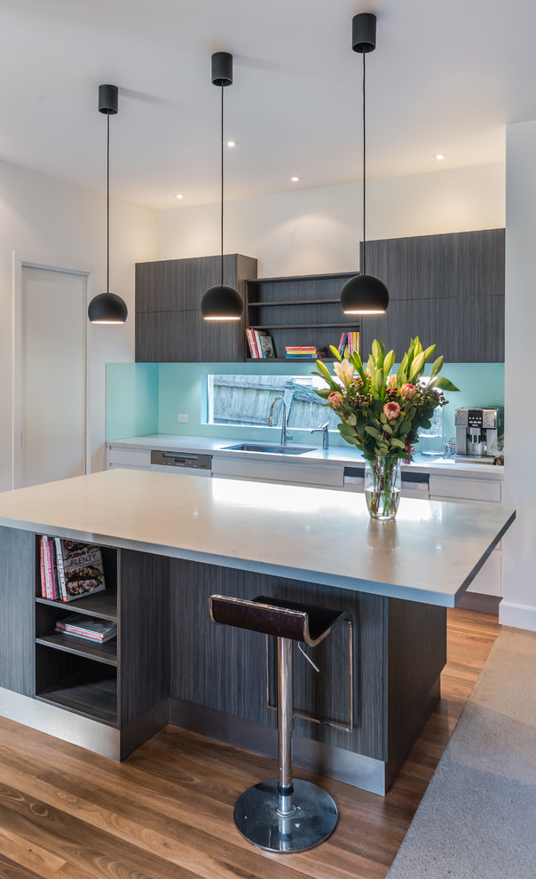 Design ideas for a large contemporary l-shaped open plan kitchen in Melbourne with an undermount sink, flat-panel cabinets, dark wood cabinets, quartz benchtops, green splashback, glass sheet splashback, stainless steel appliances, medium hardwood floors and with island.