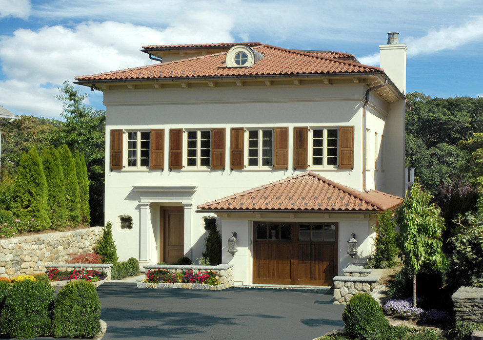 This is an example of a mediterranean two-storey white exterior in New York with a hip roof.