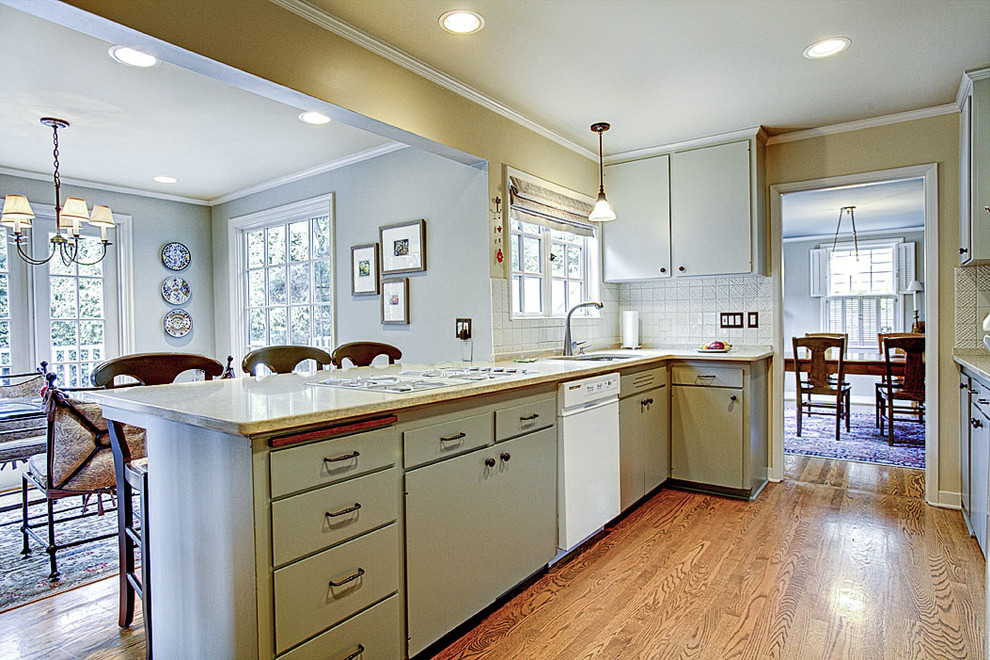 Example of a mid-sized transitional u-shaped medium tone wood floor eat-in kitchen design in Seattle with an undermount sink, flat-panel cabinets, green cabinets, quartzite countertops, white backsplash, ceramic backsplash, white appliances, gray walls and a peninsula