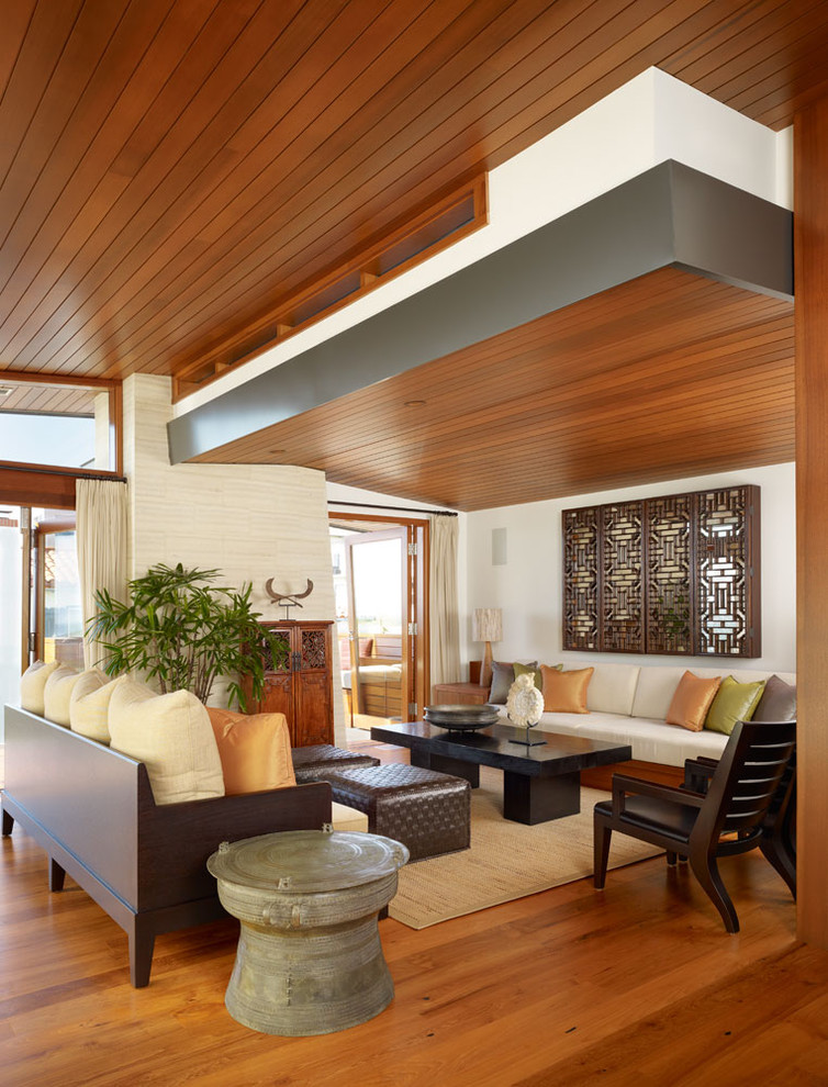 This is an example of a mid-sized tropical open concept living room in Los Angeles with a concealed tv, brown floor and dark hardwood floors.