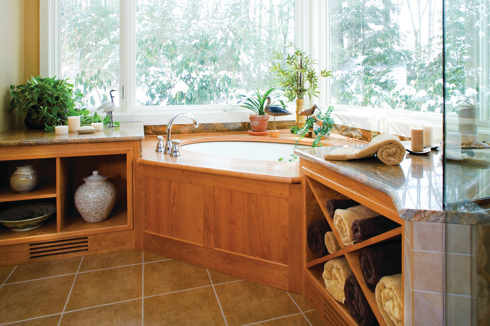 Photo of a traditional bathroom in Boston with an undermount sink, flat-panel cabinets, medium wood cabinets, granite benchtops, a drop-in tub, brown tile, porcelain tile, beige walls and porcelain floors.