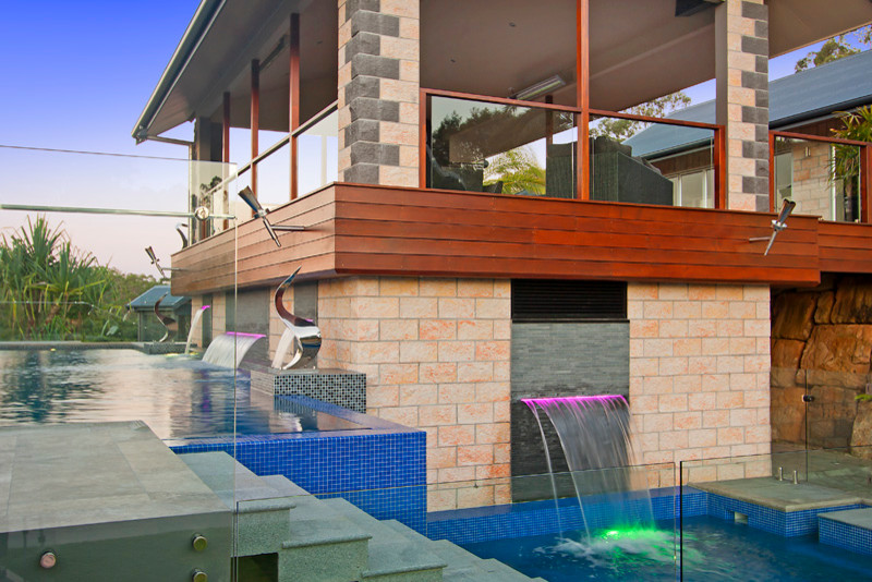 This is an example of a large contemporary backyard l-shaped aboveground pool in Brisbane with a pool house and tile.