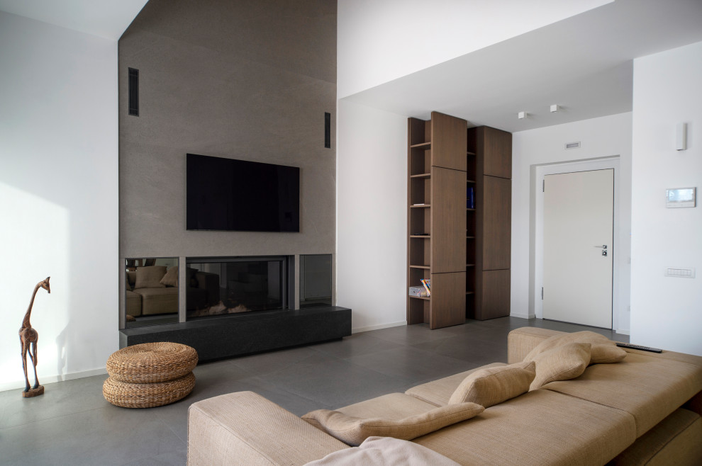 This is an example of a large contemporary formal open concept living room in Other with white walls, porcelain floors, a standard fireplace, a tile fireplace surround, a wall-mounted tv and grey floor.