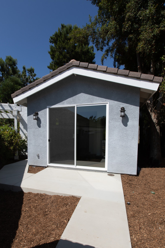 Small beach style one-storey stucco grey exterior in San Diego with a gable roof and a tile roof.