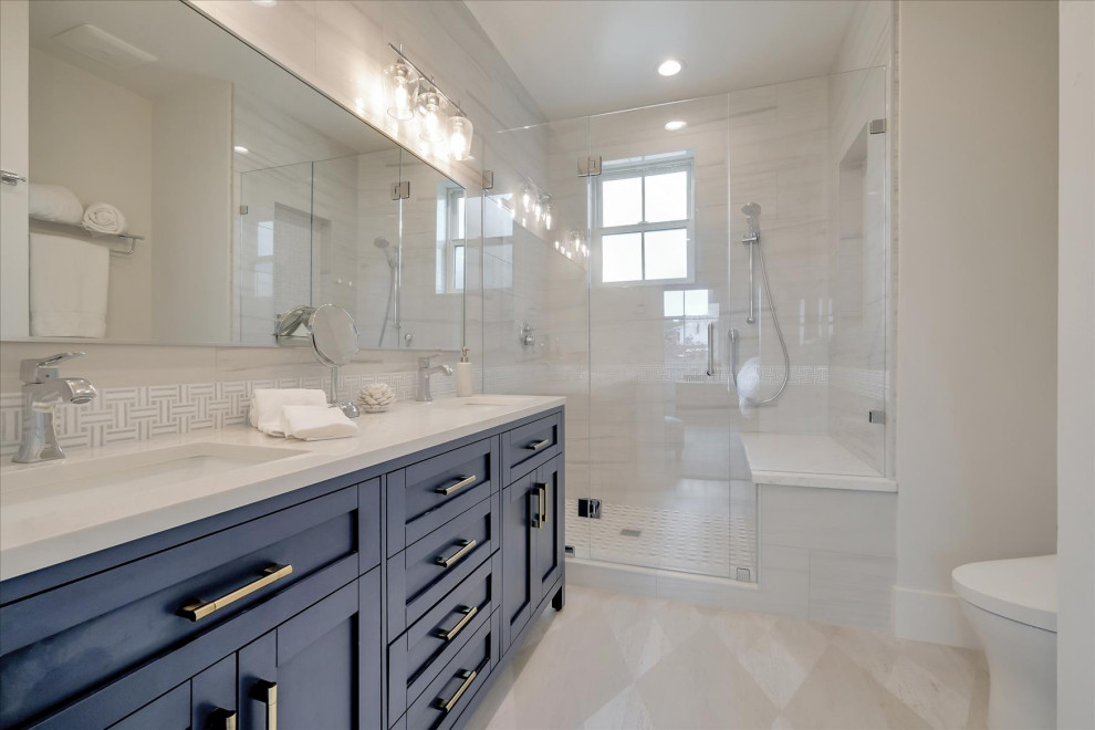 This is an example of a medium sized beach style ensuite bathroom in San Francisco with beaded cabinets, blue cabinets, an alcove shower, a two-piece toilet, white tiles, porcelain tiles, white walls, vinyl flooring, a submerged sink, engineered stone worktops, beige floors, a hinged door, white worktops, a wall niche, double sinks and a built in vanity unit.