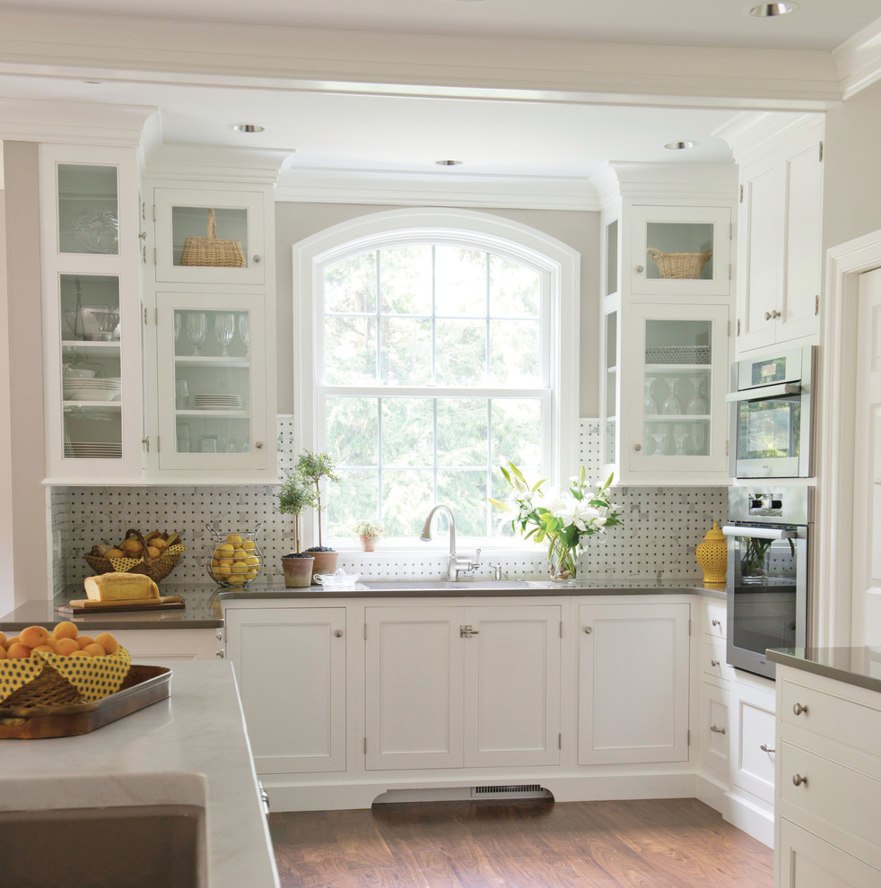 Traditional kitchen in Philadelphia with glass-front cabinets, white cabinets, quartz benchtops, stone tile splashback and multi-coloured splashback.