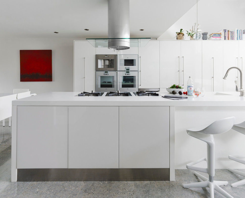 Inspiration for a large contemporary u-shaped eat-in kitchen in Vancouver with flat-panel cabinets, white cabinets, white appliances, concrete floors, with island and an undermount sink.