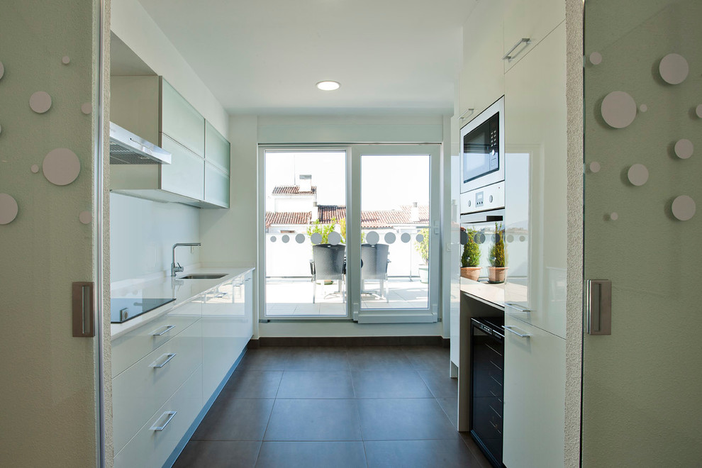 Photo of a mid-sized contemporary single-wall separate kitchen in Other with a single-bowl sink, flat-panel cabinets, white cabinets, white splashback, stainless steel appliances, ceramic floors and no island.