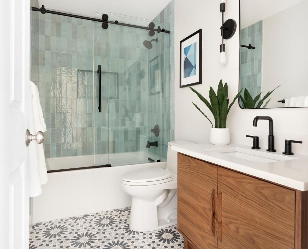 Idée de décoration pour une salle d'eau vintage en bois brun avec un placard à porte plane, une baignoire en alcôve, un combiné douche/baignoire, un mur blanc, carreaux de ciment au sol, un lavabo encastré, un sol multicolore, une cabine de douche à porte coulissante, un plan de toilette blanc, une niche, meuble simple vasque, meuble-lavabo sur pied, WC à poser, un carrelage bleu et des carreaux de porcelaine.