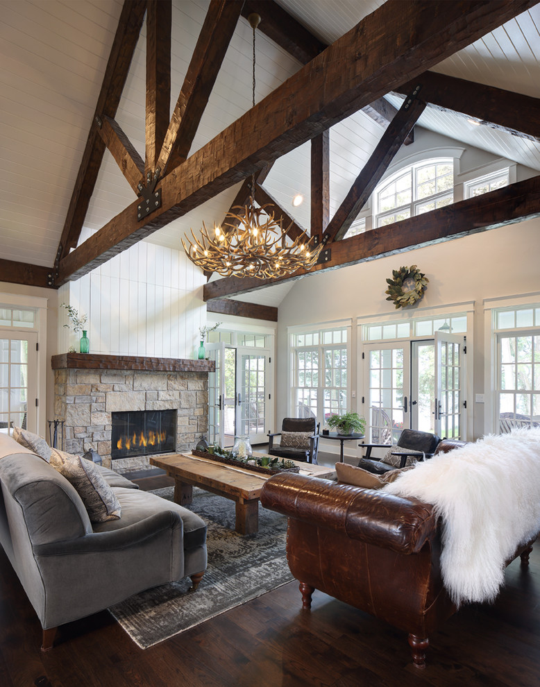 Photo of a mid-sized country open concept family room in Milwaukee with white walls, dark hardwood floors, a two-sided fireplace, a stone fireplace surround, a concealed tv and brown floor.