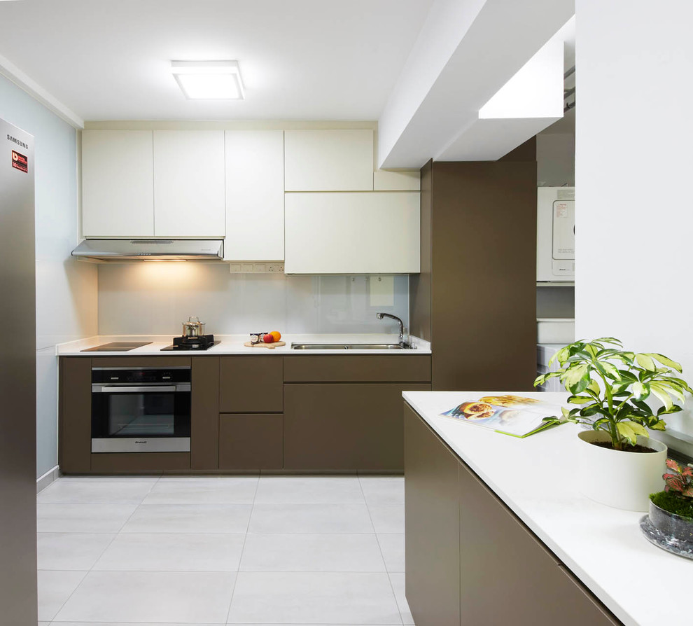 Photo of a mid-sized contemporary l-shaped kitchen pantry in Singapore with a drop-in sink, flat-panel cabinets, brown cabinets, solid surface benchtops, white splashback, glass sheet splashback, stainless steel appliances and ceramic floors.