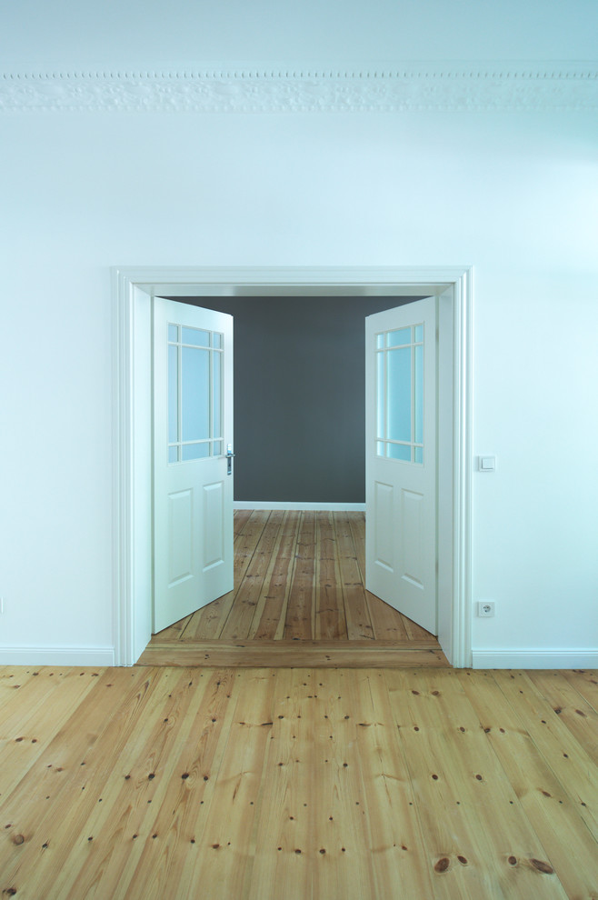 Mittelgroßes, Repräsentatives, Fernseherloses, Offenes Modernes Wohnzimmer ohne Kamin mit weißer Wandfarbe, hellem Holzboden und beigem Boden in Berlin