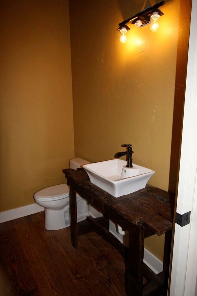 Small mountain style 3/4 medium tone wood floor and brown floor bathroom photo with brown cabinets, a two-piece toilet, yellow walls, a vessel sink and wood countertops