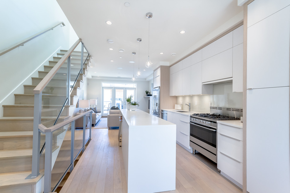 Design ideas for a contemporary single-wall kitchen in Vancouver with an undermount sink, flat-panel cabinets, white cabinets, grey splashback and light hardwood floors.