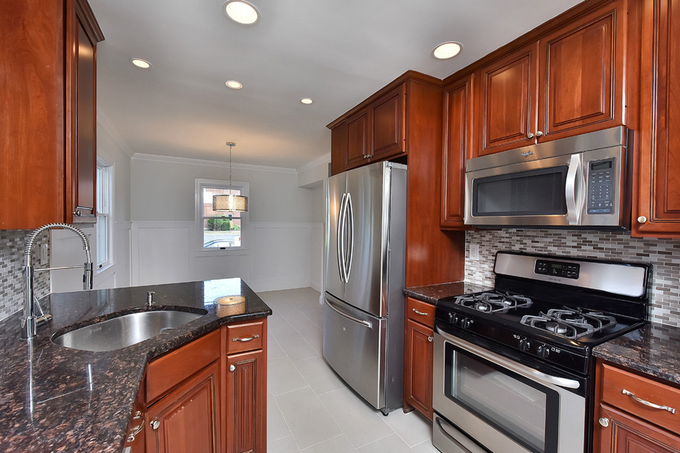 Example of a mid-sized transitional galley kitchen design with a single-bowl sink, raised-panel cabinets, medium tone wood cabinets, gray backsplash, stainless steel appliances and no island