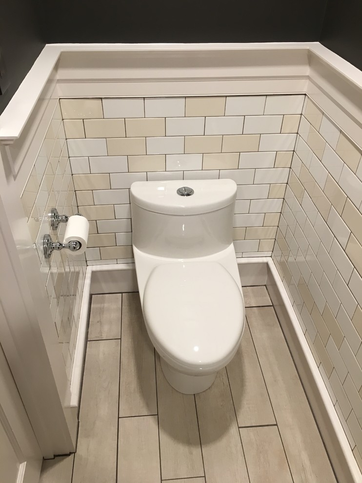 Small contemporary powder room in Boston with raised-panel cabinets, distressed cabinets, a one-piece toilet, white tile, ceramic tile, brown walls, ceramic floors, an undermount sink, granite benchtops and beige floor.