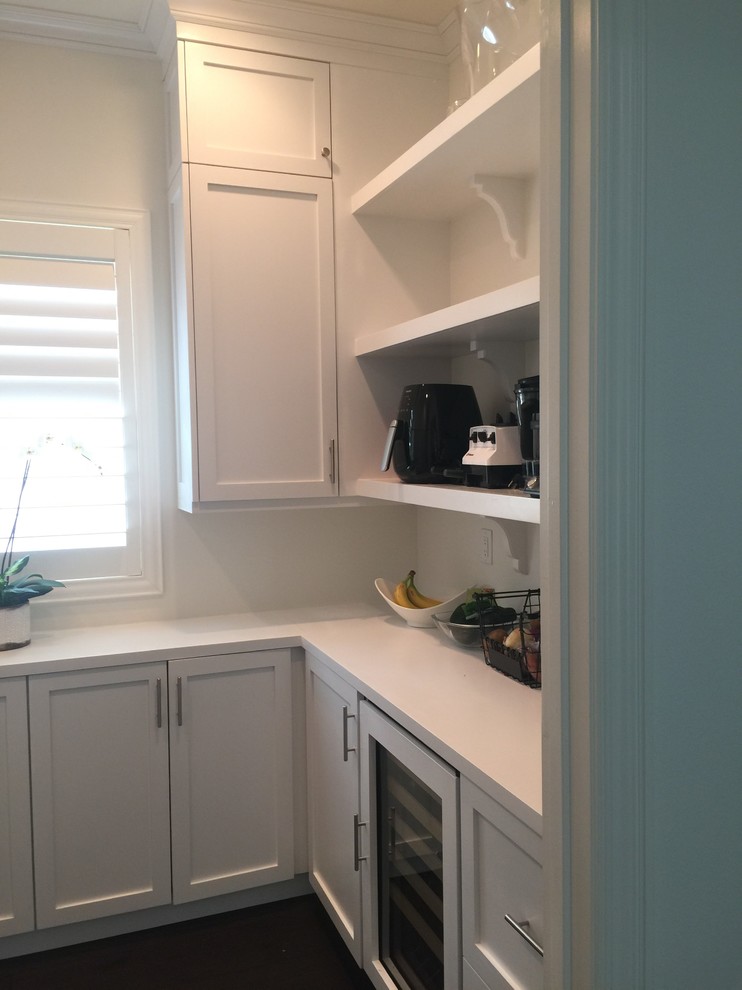 Photo of a large transitional u-shaped kitchen pantry in Orange County with recessed-panel cabinets, white cabinets, solid surface benchtops and dark hardwood floors.