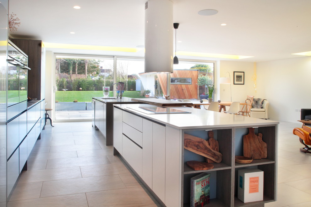 Large contemporary single-wall open plan kitchen in Buckinghamshire with flat-panel cabinets, grey cabinets, quartzite benchtops, timber splashback, stainless steel appliances, porcelain floors, with island and an integrated sink.