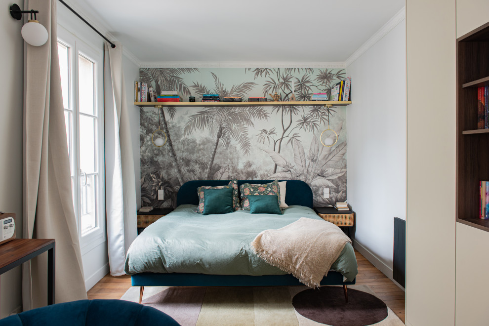 Cette photo montre une petite chambre parentale tendance avec un mur blanc, parquet clair et du papier peint.