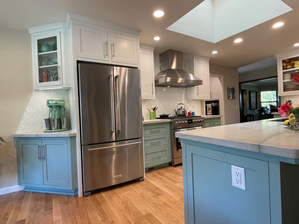 Photo of a large transitional l-shaped open plan kitchen in Other with an undermount sink, shaker cabinets, turquoise cabinets, quartzite benchtops, white splashback, porcelain splashback, stainless steel appliances, medium hardwood floors, with island, brown floor and white benchtop.