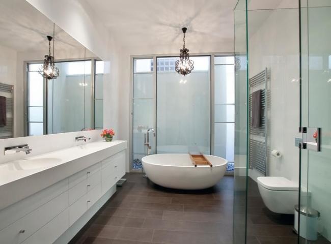 Inspiration for a large modern bathroom in Melbourne with an integrated sink, flat-panel cabinets, white cabinets, engineered quartz benchtops, a freestanding tub, an open shower, porcelain tile, white walls, porcelain floors, a wall-mount toilet and white tile.