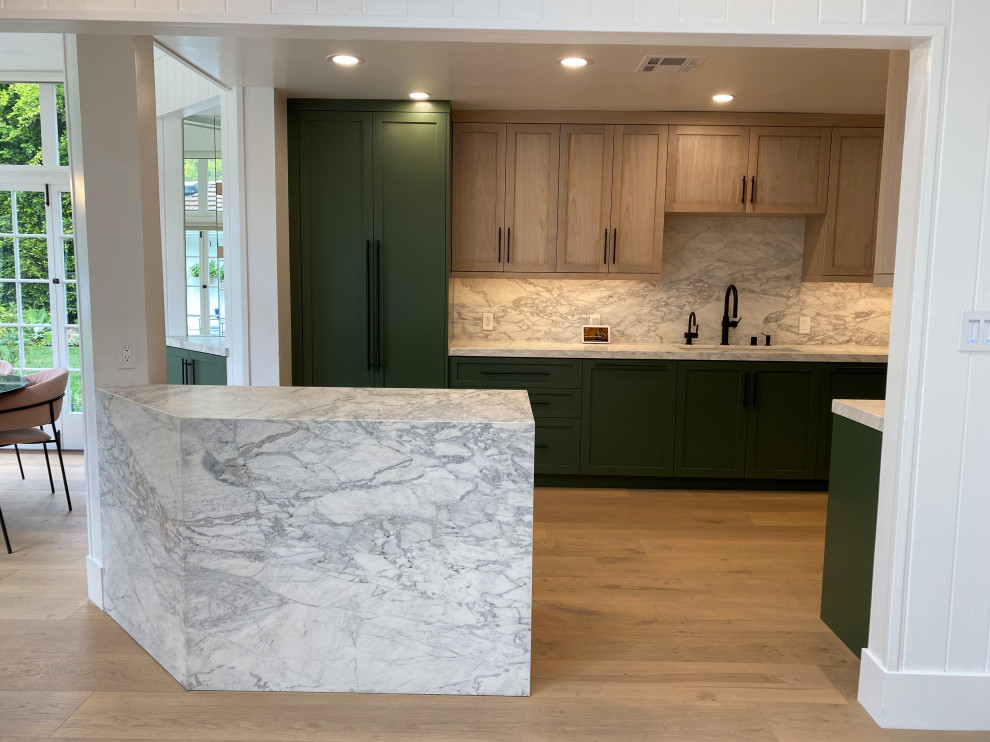 Example of a classic galley light wood floor and white floor eat-in kitchen design with an integrated sink, shaker cabinets, green cabinets, marble countertops, white backsplash, marble backsplash, paneled appliances, an island and white countertops