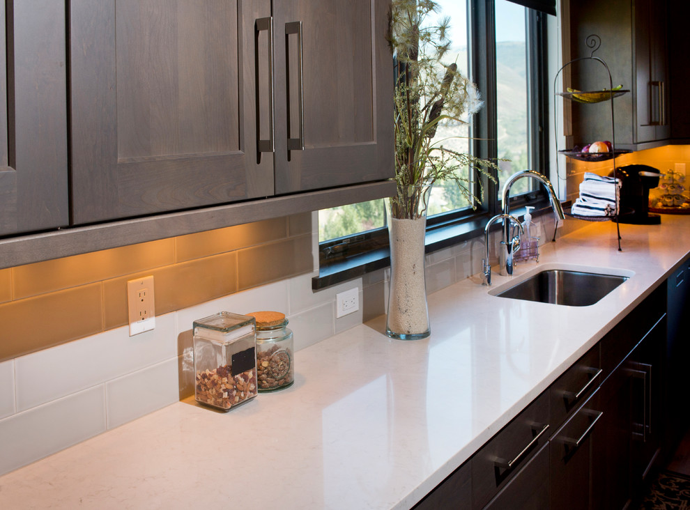 Large transitional u-shaped medium tone wood floor eat-in kitchen photo in Denver with an undermount sink, recessed-panel cabinets, gray cabinets, quartz countertops, white backsplash, ceramic backsplash, stainless steel appliances and two islands