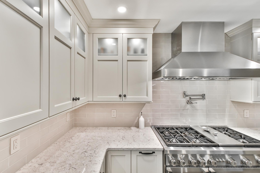 Inspiration for a transitional l-shaped utility room in Philadelphia with a drop-in sink, recessed-panel cabinets, white cabinets, laminate benchtops, beige splashback, subway tile splashback, a side-by-side washer and dryer and white benchtop.
