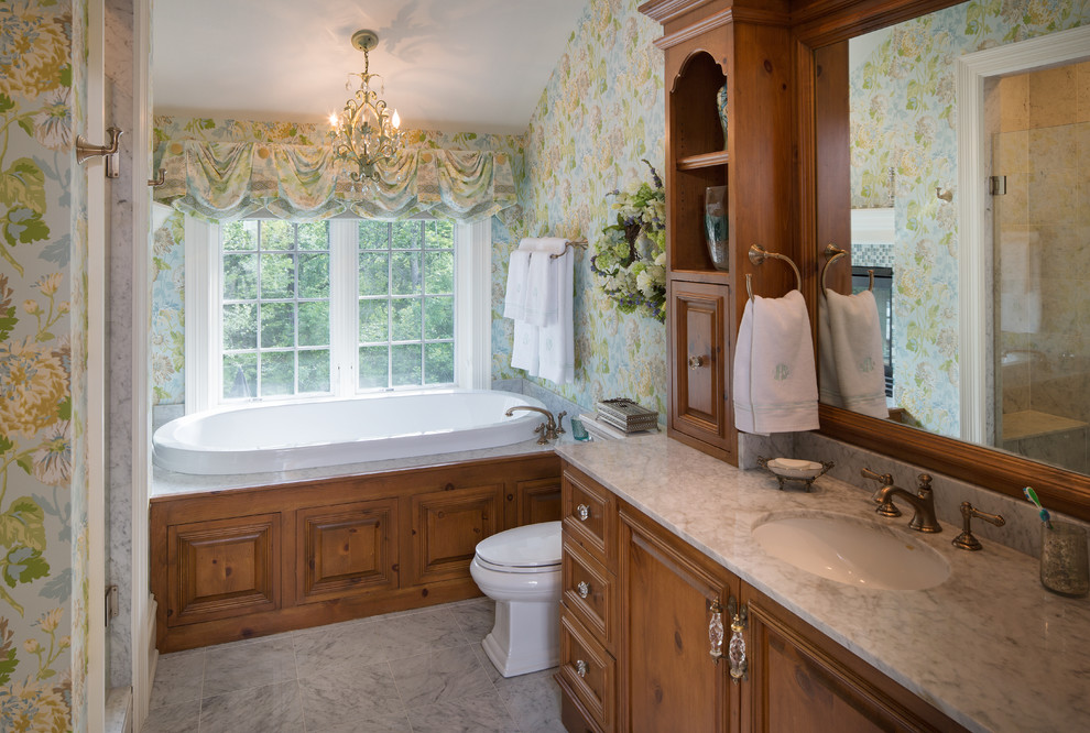 Large transitional master bathroom in Indianapolis with raised-panel cabinets, medium wood cabinets, an alcove tub, an alcove shower, a two-piece toilet, multi-coloured tile, stone tile, multi-coloured walls, marble floors, an undermount sink and marble benchtops.