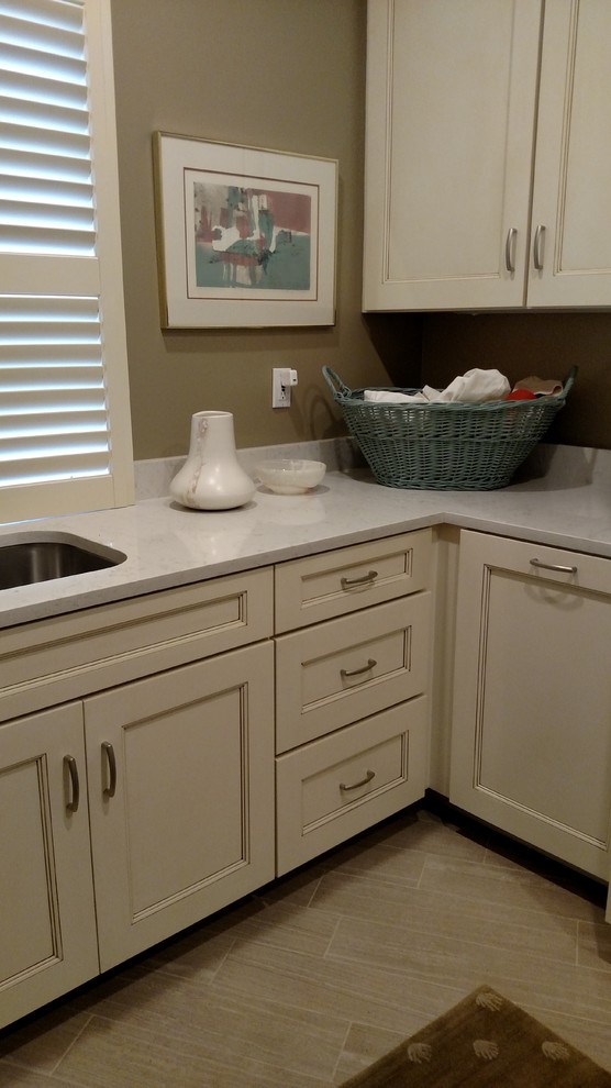 Example of a transitional ceramic tile laundry room design with an undermount sink, recessed-panel cabinets, beige cabinets, quartz countertops and gray walls