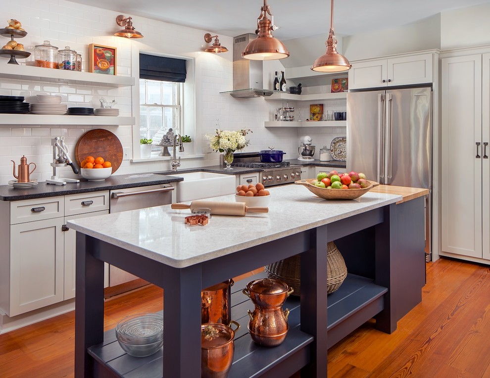 Photo of a country l-shaped kitchen in Other with a farmhouse sink, shaker cabinets, solid surface benchtops, white splashback, subway tile splashback, stainless steel appliances, medium hardwood floors and with island.