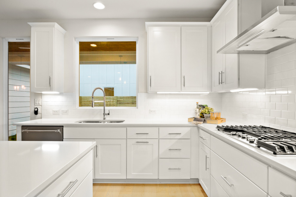 Inspiration för ett lantligt vit vitt kök, med luckor med infälld panel, vita skåp, rostfria vitvaror, ljust trägolv, en köksö, vitt stänkskydd och stänkskydd i tunnelbanekakel