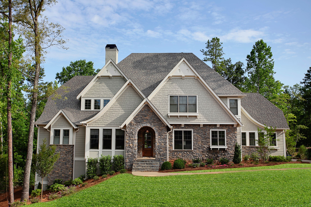 This is an example of a large traditional two-storey beige exterior in Charlotte with stone veneer and a hip roof.