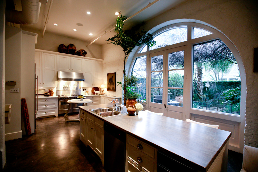 Example of a large transitional l-shaped porcelain tile and brown floor eat-in kitchen design in Miami with a drop-in sink, shaker cabinets, white cabinets, wood countertops, white backsplash, stone tile backsplash, stainless steel appliances and an island