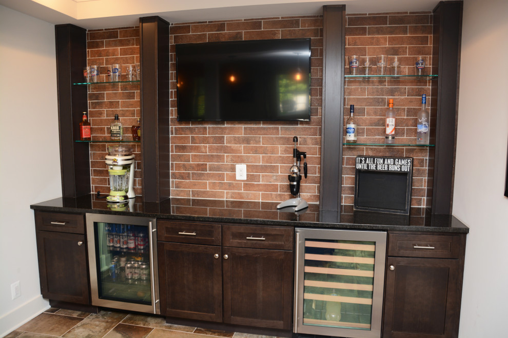 Photo of a mid-sized traditional u-shaped seated home bar in Baltimore with an undermount sink, recessed-panel cabinets, dark wood cabinets, granite benchtops, red splashback, brick splashback, brown floor and black benchtop.